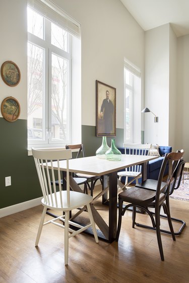 Eclectic dining room with vintage style chairs, table, glass vases, vintage art, green and white wall.